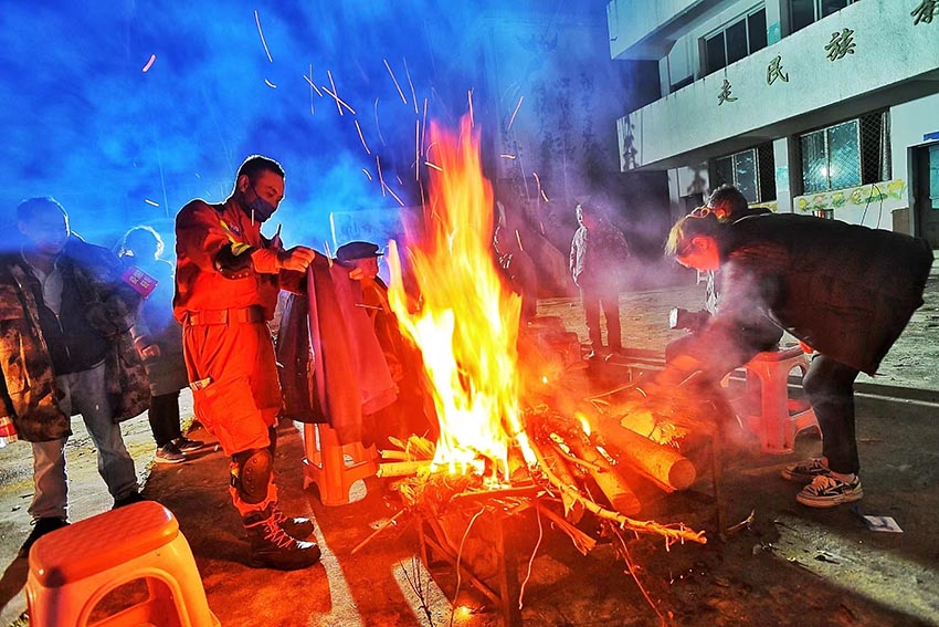 9月5日深夜，消防救援人員在燕子溝鄉(xiāng)排查時(shí)烤干衣服。四川省消防救援總隊(duì)供圖