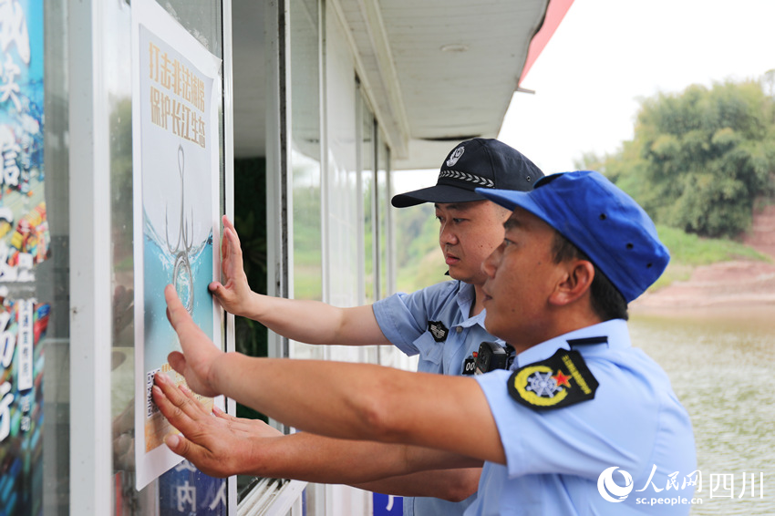 長江航運公安民警與漁政協(xié)助巡護隊員一同張貼“禁捕”宣傳海報。人民網(wǎng) 趙祖樂攝
