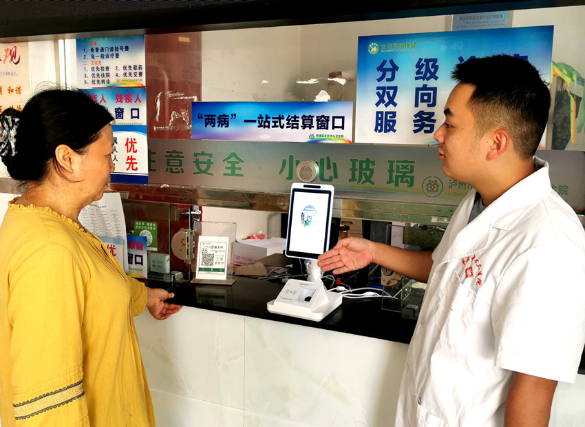 醫(yī)務(wù)人員引導(dǎo)群眾“刷臉”結(jié)算醫(yī)療費(fèi)用。納溪區(qū)醫(yī)保局供圖