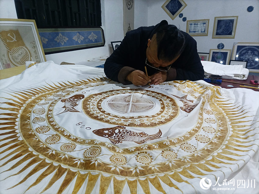 楊安平在蠟布上刻畫圖案。曾剛攝