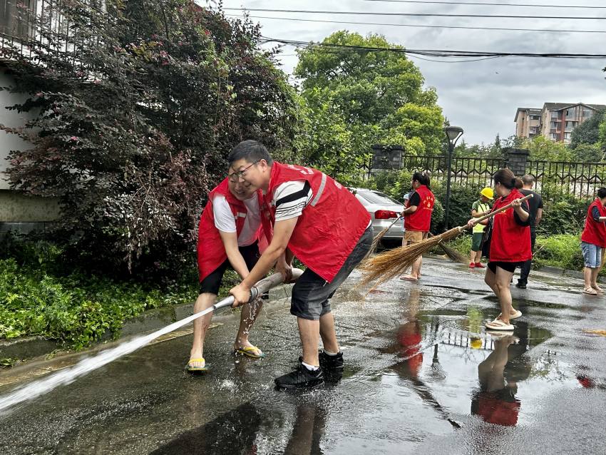 程平（左二）與社區(qū)工作人員一同清理小區(qū)淤泥。都江堰市融媒體中心供圖