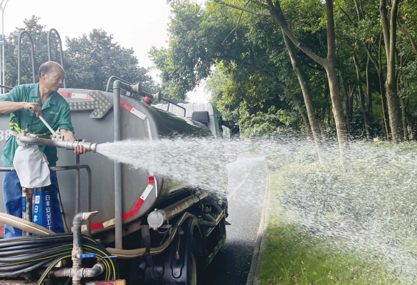 綠化工人站在灑水車上澆灌綠植。曾剛攝