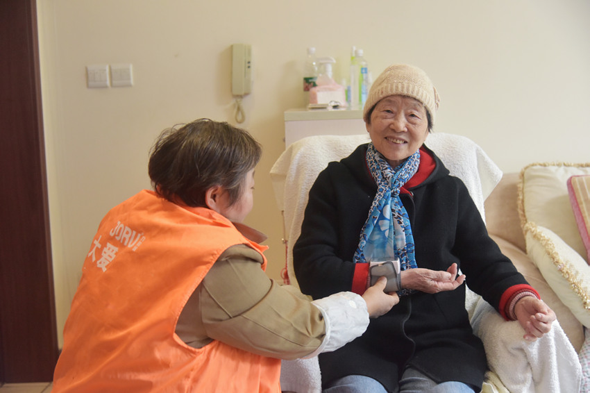 護工“香香”正在給魏秀蘭測血壓。蒲訓訓供圖