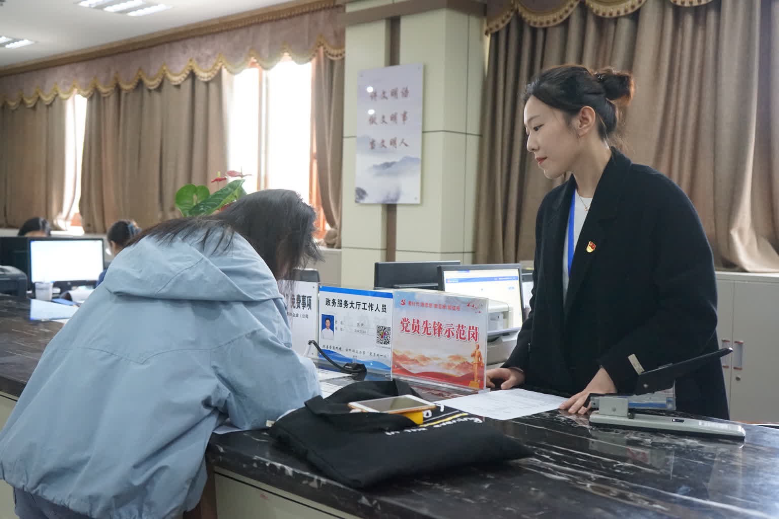 在高坪區(qū)行政審批辦事大廳，工作人員正在指導(dǎo)申辦人填寫表格。高坪區(qū)融媒體中心供圖