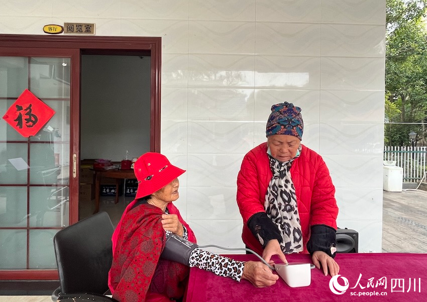 村里康養(yǎng)老人互幫互助，圖為謝阿姨正在跟朋友測量血壓。人民網(wǎng)記者郭瑩攝