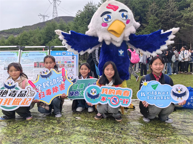 當?shù)貙W生和涼山禁毒IP“火洛”合影。美姑縣委禁毒辦供圖