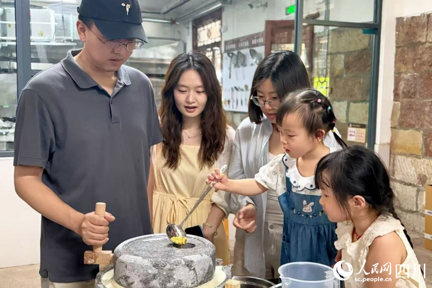 參加研學(xué)的孩子在家長(zhǎng)的陪同下，上手體驗(yàn)先市醬油制作（部分環(huán)節(jié)）。楊藺攝